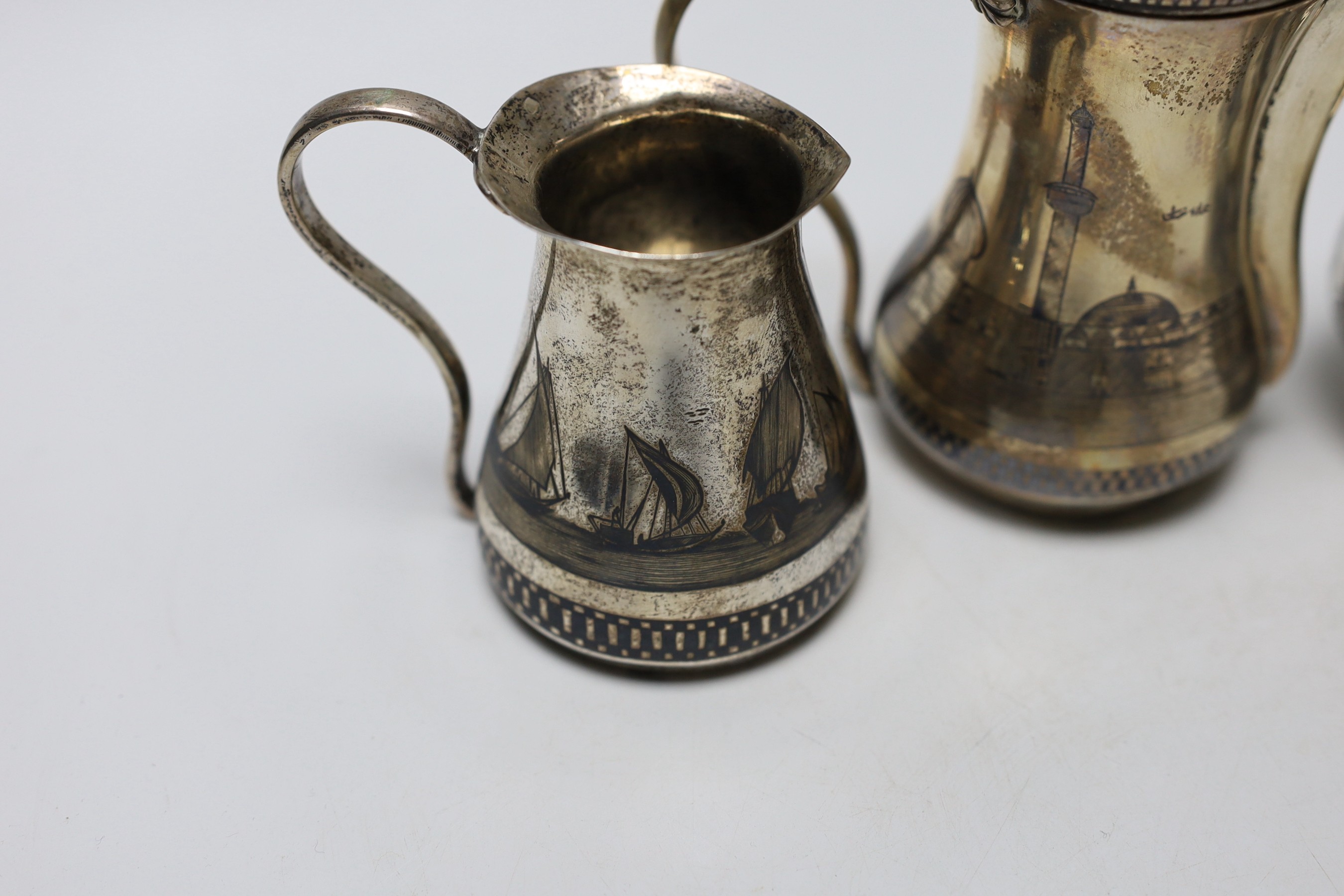 A Middle Eastern white metal and niello cream jug, a sugar bowl and coffee pot, 16.4cm, gross weight 22oz.